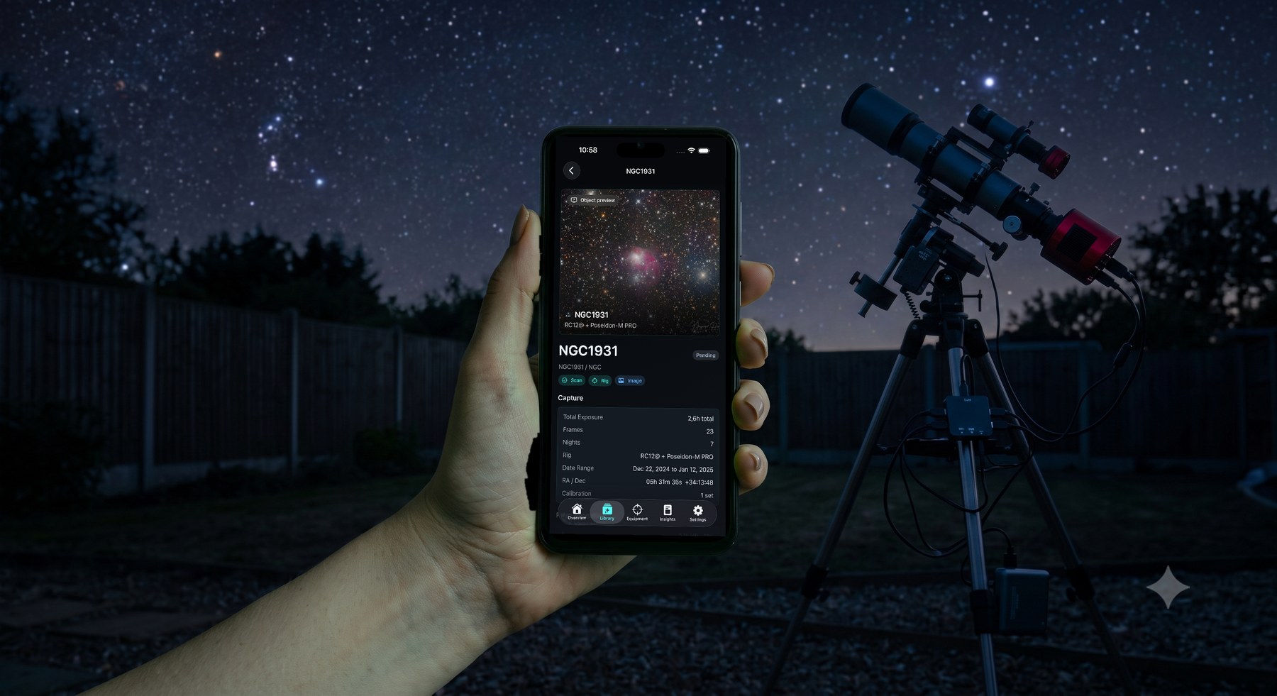 A hand holding a phone running the AstroIndexer companion app at night, showing the NGC1931 object page, with a telescope rig under a starry sky